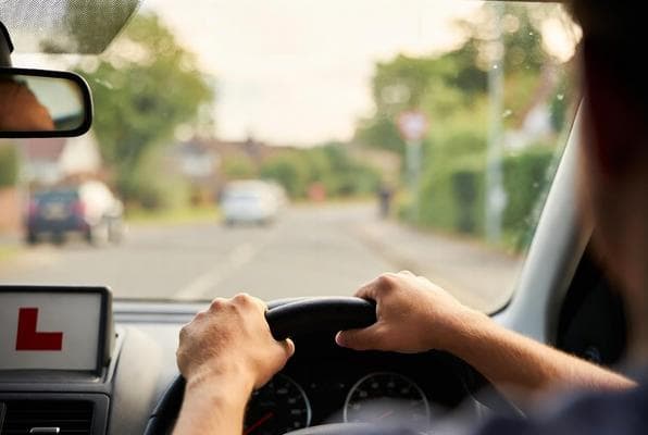 Learner driver at the wheel with L-plate