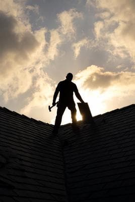 Roofer silhouetted against sky